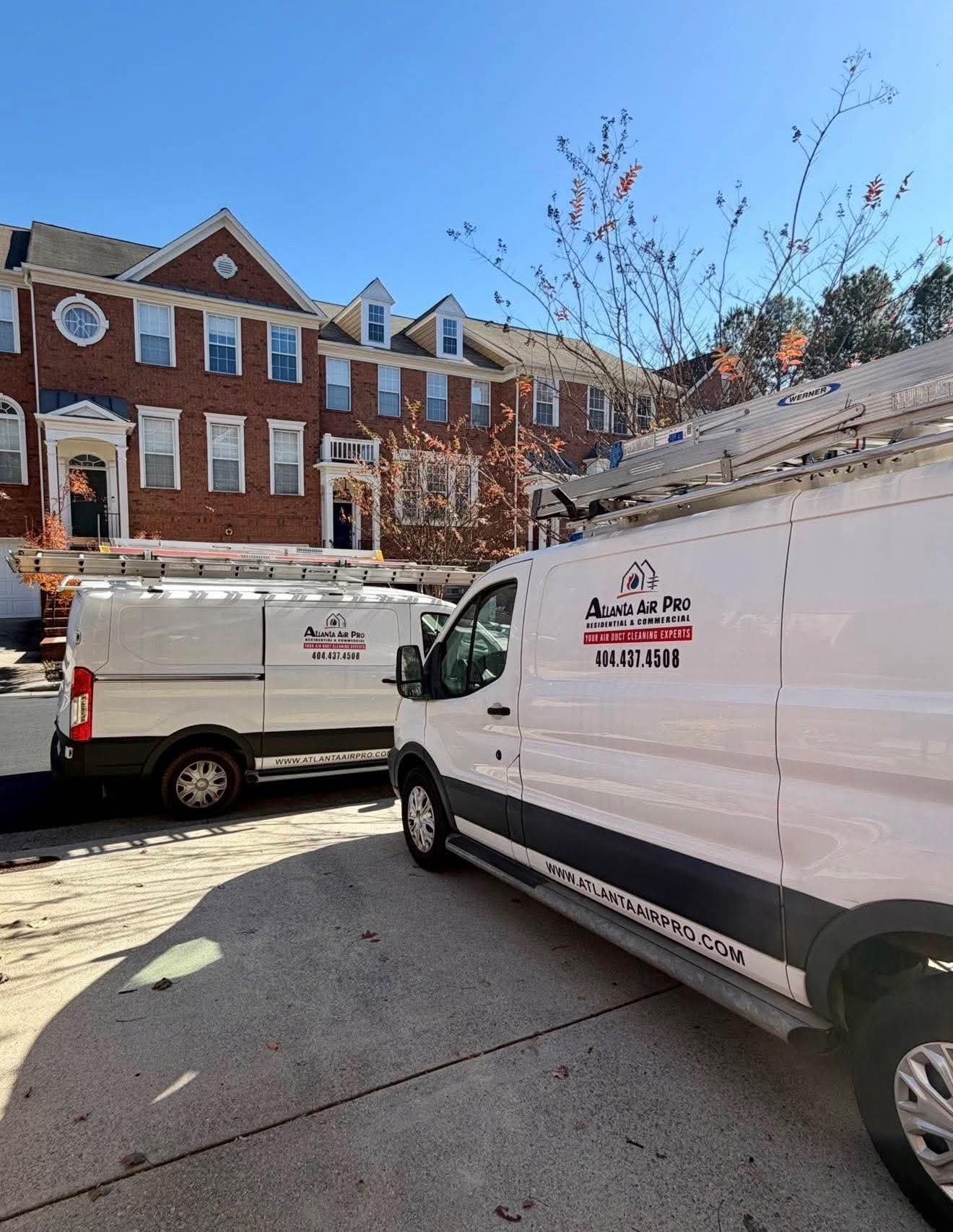 Two Atlanta Air Pro service vans parked outside a residential townhouse for an air duct cleaning appointment