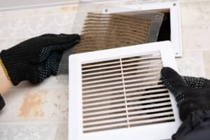 Technician removing a dirty air vent cover for cleaning.