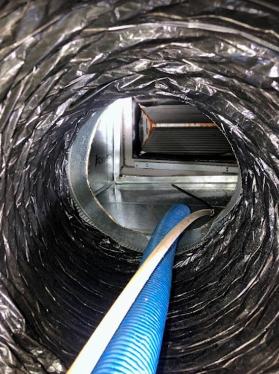 Clean air duct with a cleaning hose inside, showing ongoing air duct cleaning process.