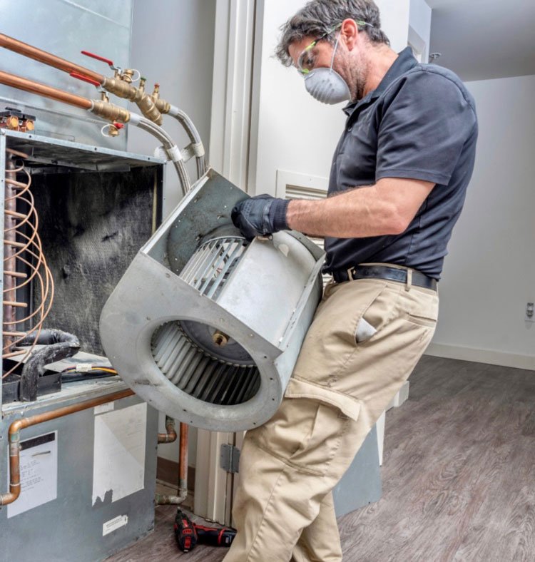 Technician performing blower motor cleaning as part of HVAC maintenance.