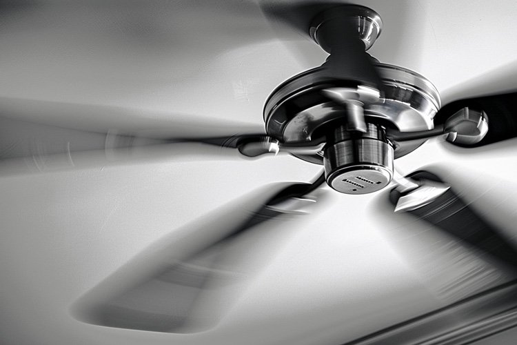 Ceiling fan spinning in a sunlit room, providing supplementary cooling.