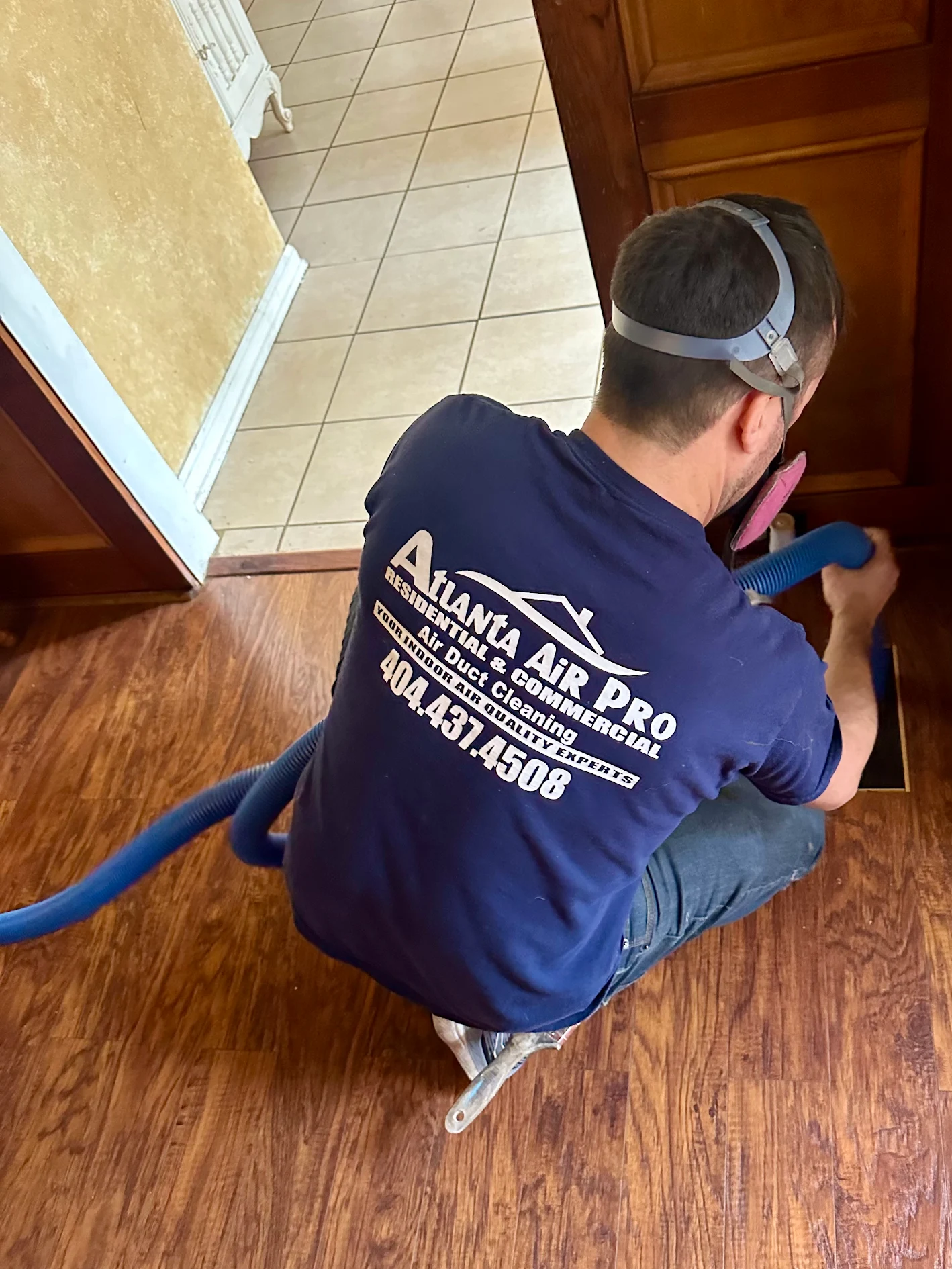 Atlanta Air Pro technician cleaning a residential floor register with a flexible vacuum hose
