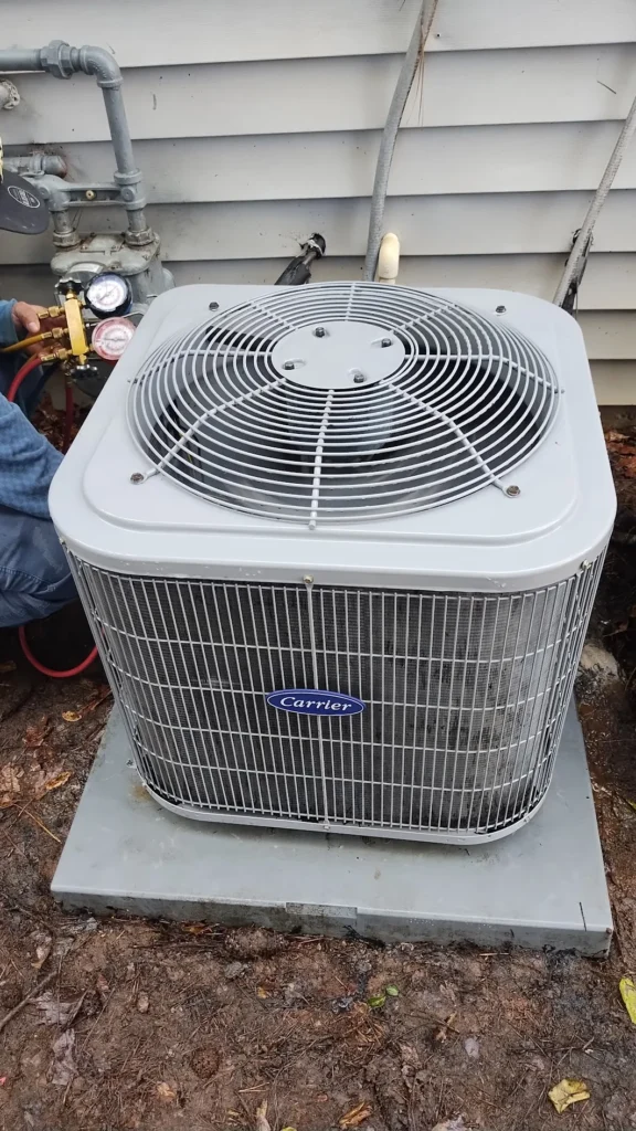 Carrier outdoor AC condenser after professional cleaning with a technician checking the system pressure
