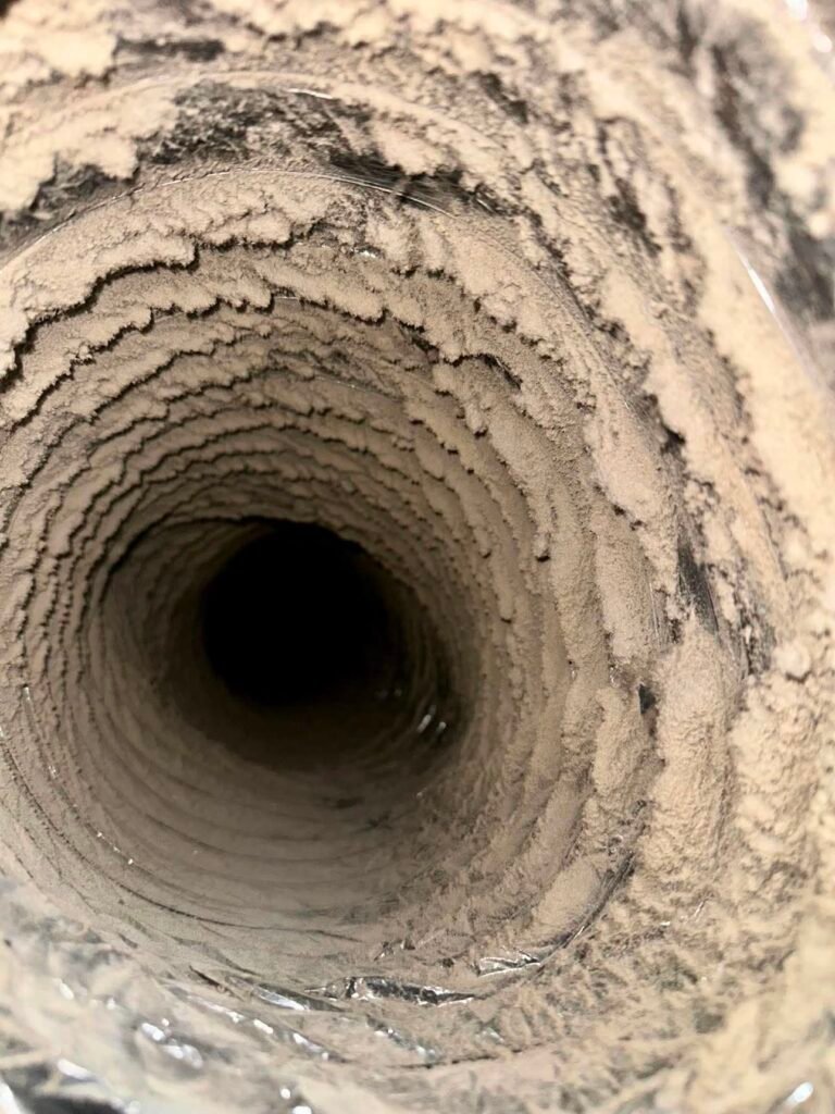 Severe dust buildup coating the interior walls of a residential flexible air duct before professional cleaning